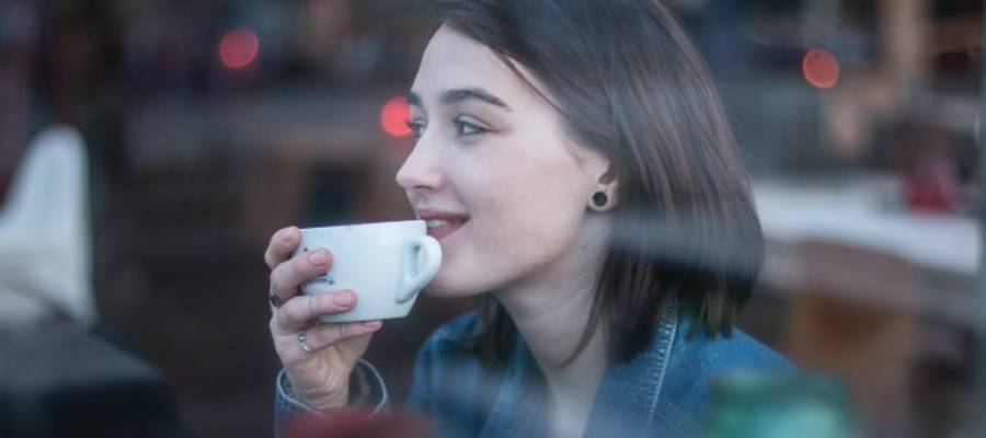 woman smiling over coffee cup woman smiling over coffee cup