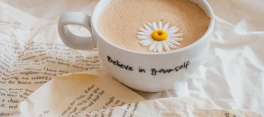 crumpled manuscript pages and cup with the words Believe in Yourself