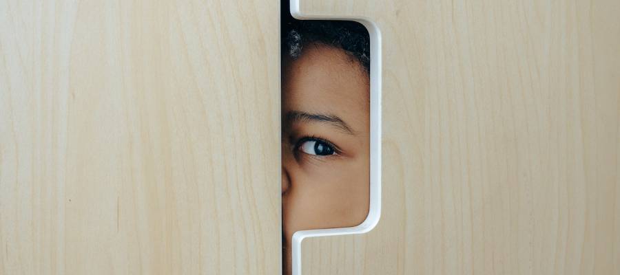 woman peering out of gap in door woman peering out of gap in door