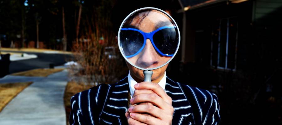 woman peering through magnifying glass woman peering through magnifying glass