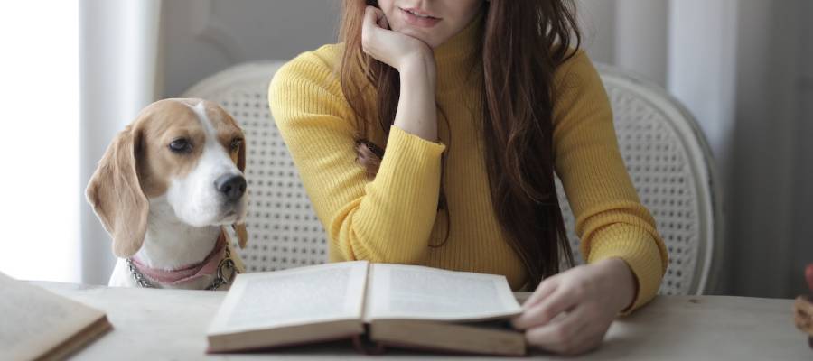 woman and beagle looking at open book