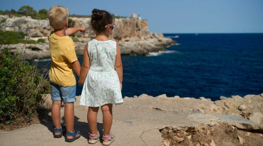 boy pointing to the ocean boy showing something to a girl