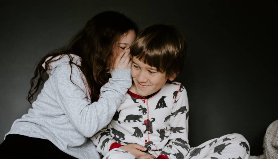 A girl whispers in a boy's ear. two children whispering together
