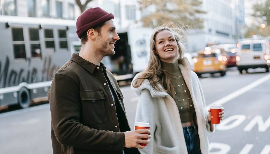 man and woman talking as they cross a street